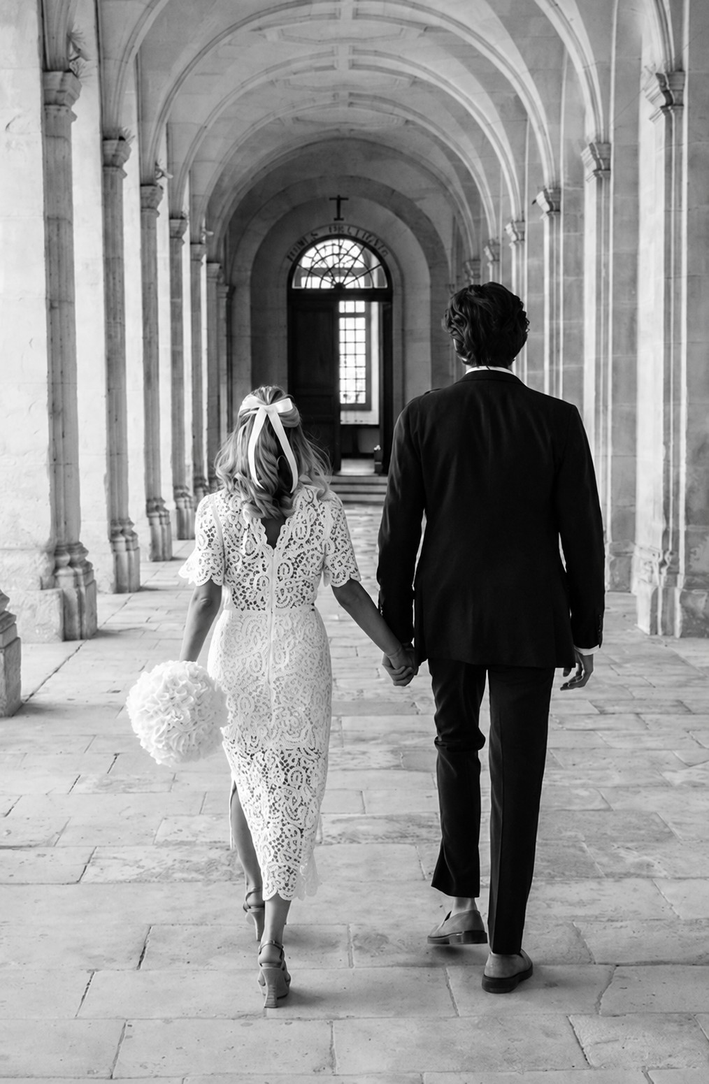 Mari&eacute;s de dos sous une galerie vo&ucirc;t&eacute;e, en noir et blanc