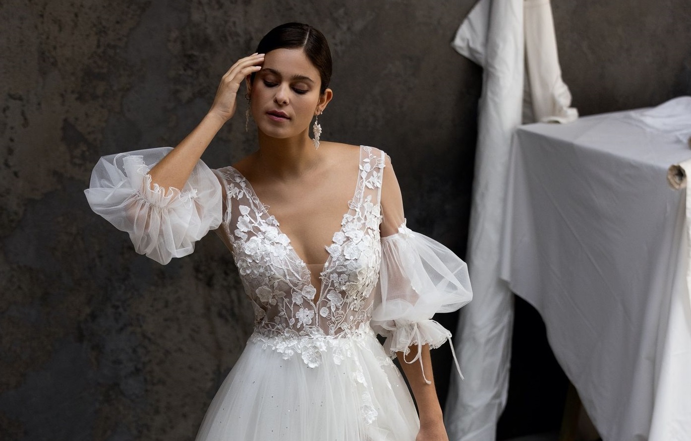 Une robe de mariée princesse 2025 en tulle pailleté à manches amovibles. Le décolleté à bretelles effet illusion est parsemé d’incrustations de tulle brodé aux motifs fleuris.