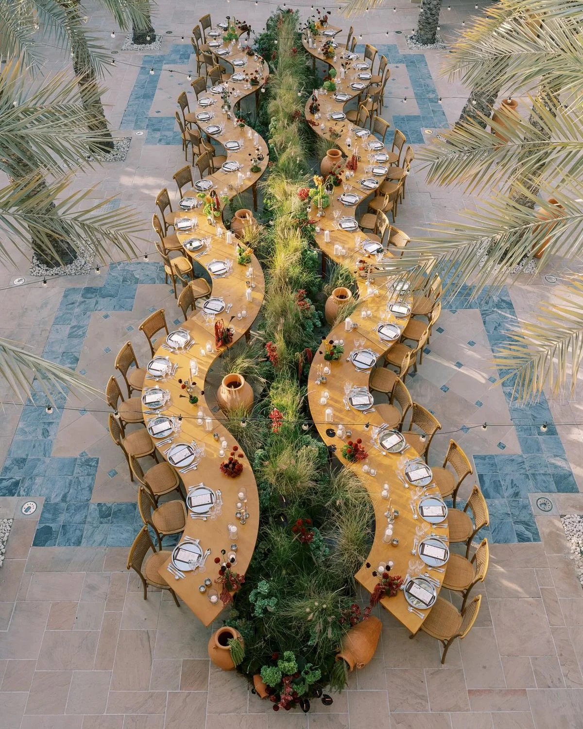 repas de mariage en serpentin avec la décoration florale entre les tables